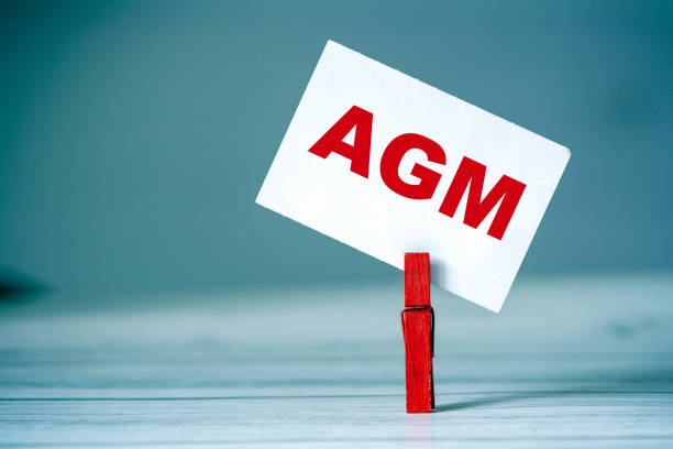 Reminder sticky note with clothes pin on table. Sticky note with word AGM. Business strategy concept